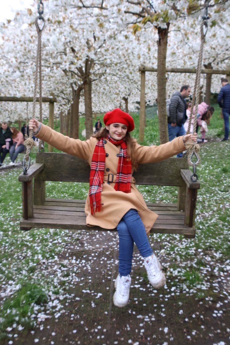 On a swing in a cherry orchard in full white blossom.
