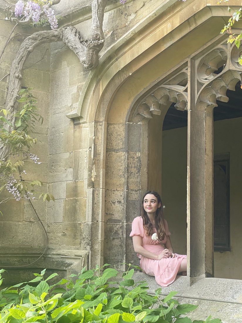 Sitting in a stone archway under trailing wisteria.